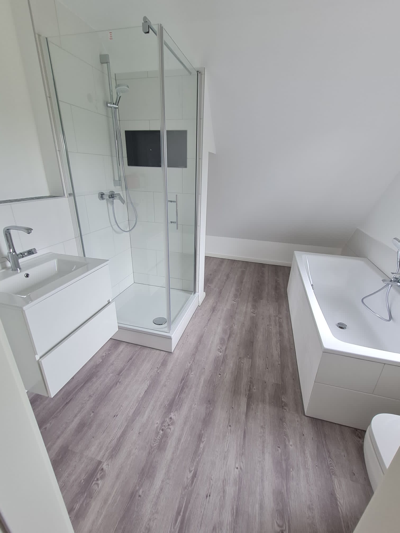 Helles Bad mit Dusche und Badewanne unter der Dachschräge